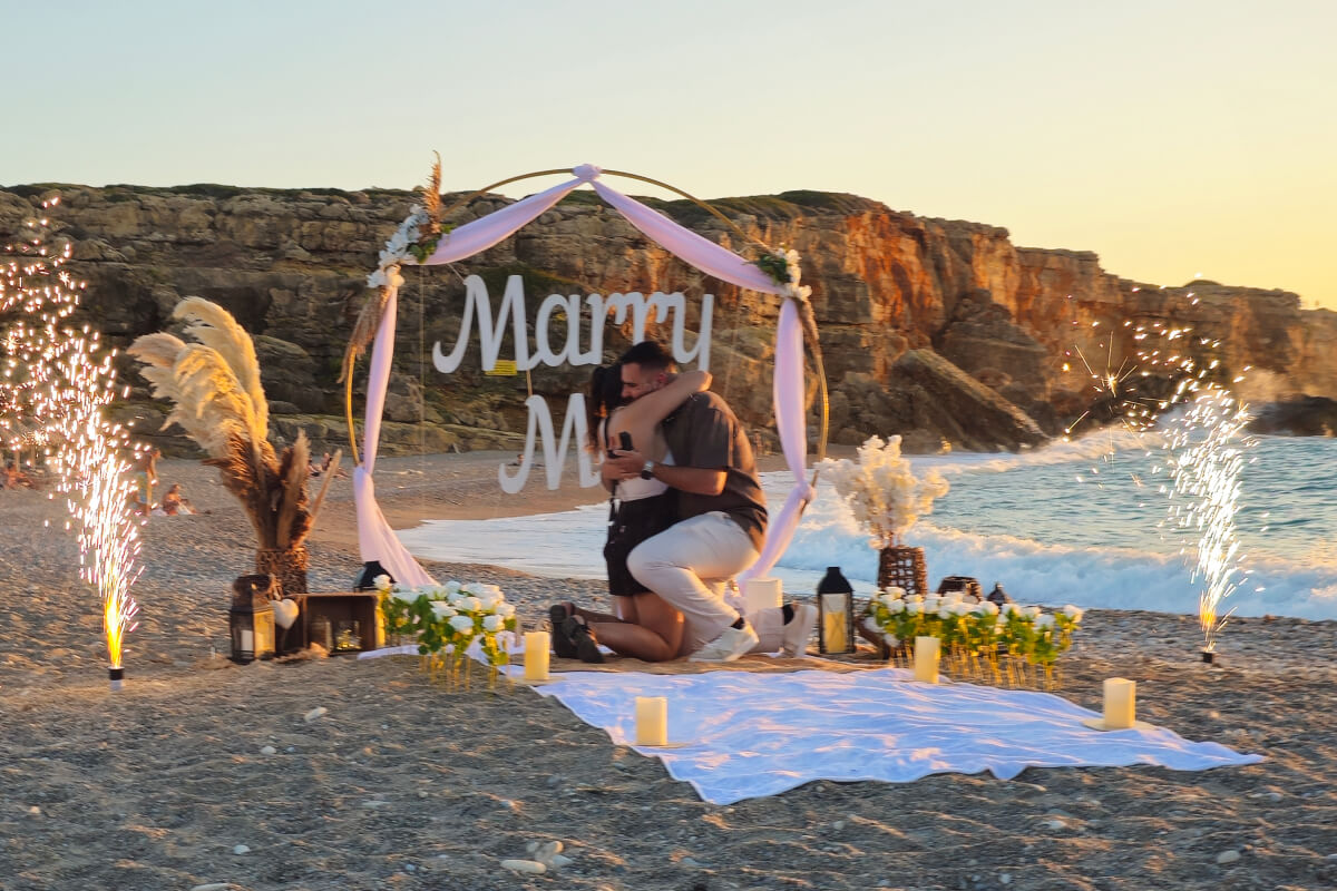 Luxury beach marriage proposal in Crete at sunset with decorated setup and couple