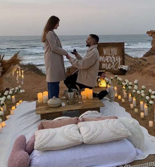 Romantic proposal setup with candles and ocean view at sunset